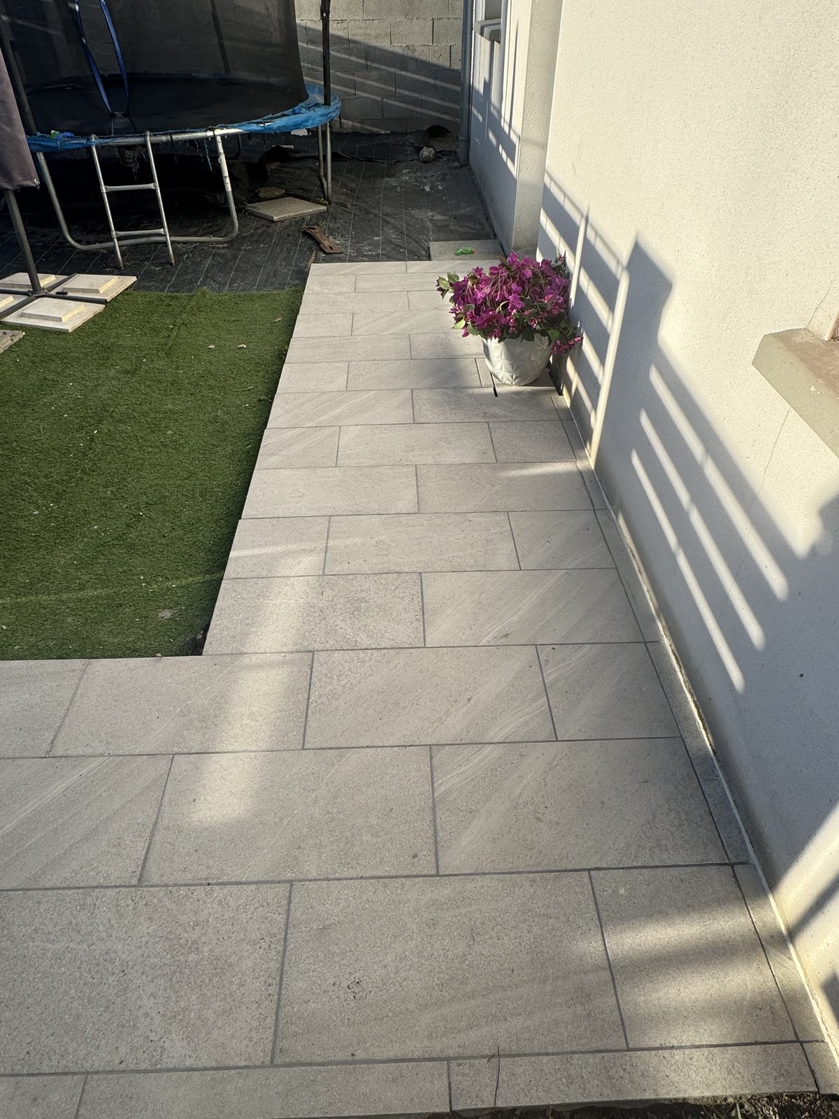 Passage extérieur en carrelage clair le long d'une maison